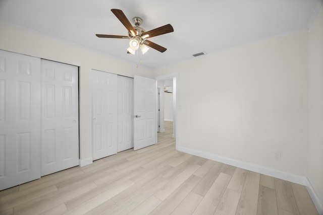 unfurnished bedroom featuring multiple closets, ceiling fan, and light hardwood / wood-style flooring