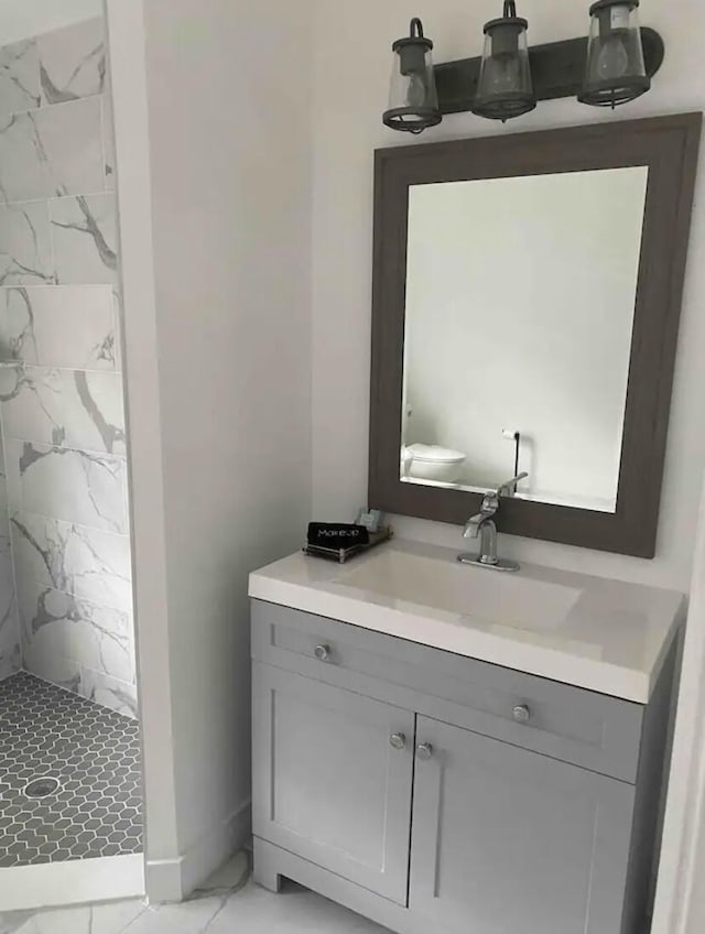 bathroom with a tile shower and vanity