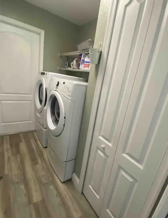 laundry area featuring separate washer and dryer and light hardwood / wood-style flooring