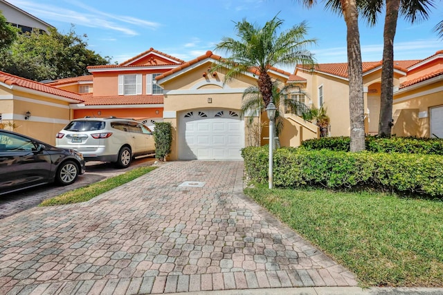 view of front of property with a garage, a tile roof, decorative driveway, and stucco siding