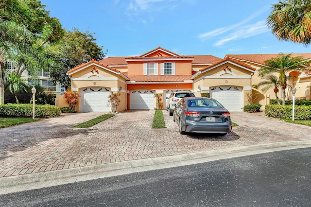 view of front facade with driveway, a tile roof, an attached garage, and stucco siding