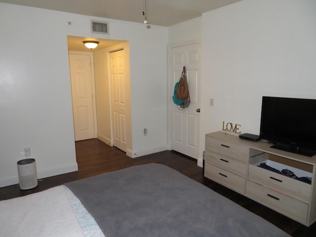 bedroom with dark wood-style floors, visible vents, and baseboards