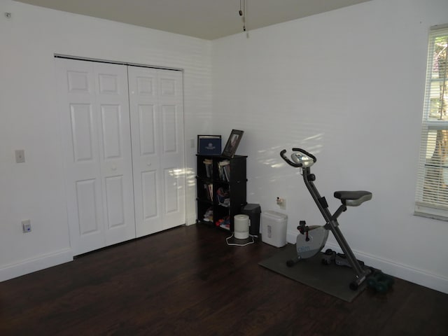 exercise room with dark wood finished floors and baseboards