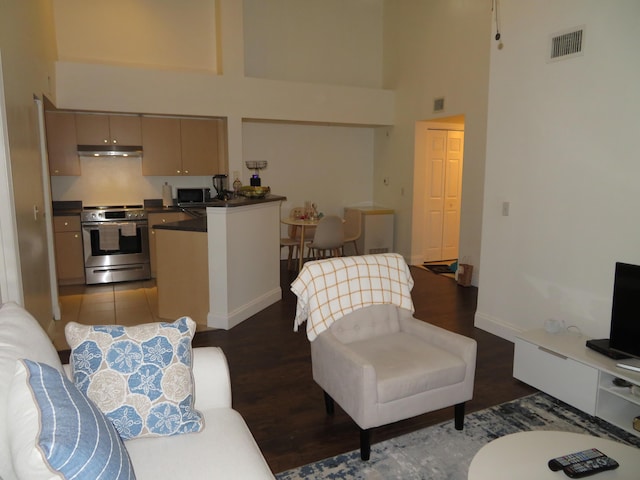 living area featuring a towering ceiling, baseboards, visible vents, and dark wood-style flooring