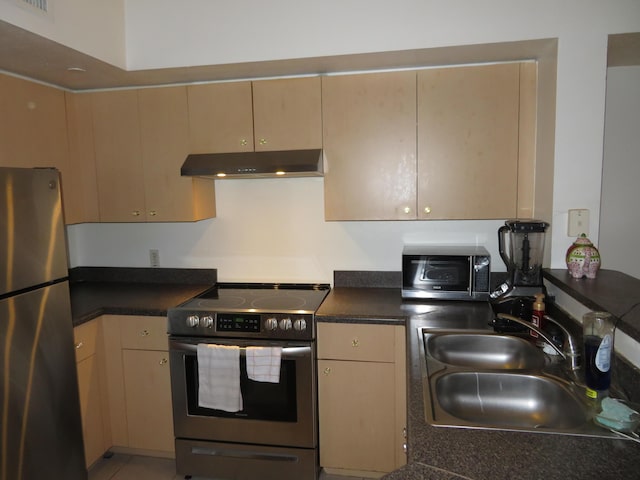 kitchen with stainless steel appliances, dark countertops, light brown cabinetry, a sink, and under cabinet range hood