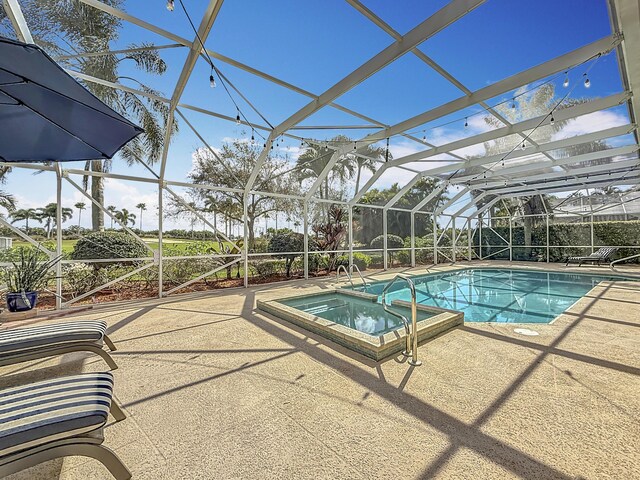 view of pool featuring a pool with connected hot tub, glass enclosure, and a patio