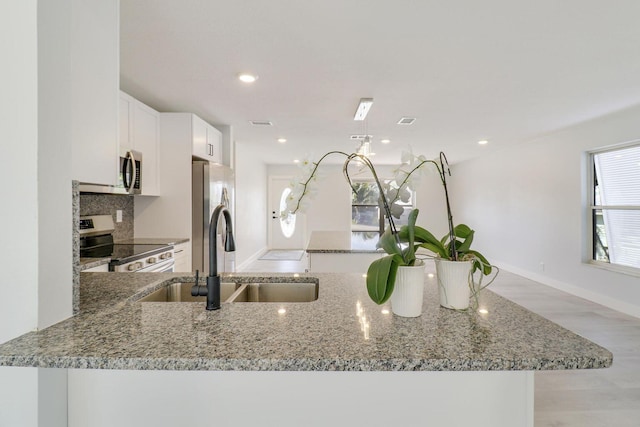 kitchen featuring light stone counters, stainless steel appliances, sink, and white cabinets