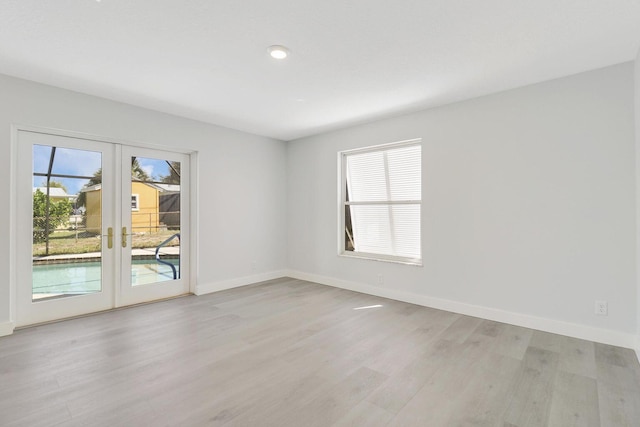 spare room featuring light hardwood / wood-style floors, french doors, and a healthy amount of sunlight