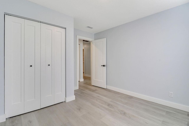 unfurnished bedroom featuring light wood-type flooring and a closet