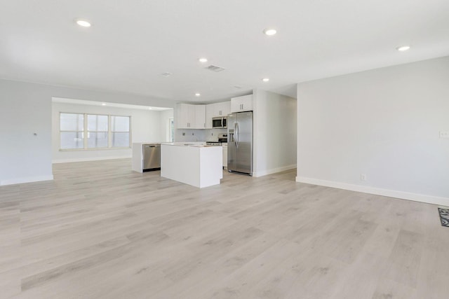 kitchen featuring white cabinetry, stainless steel appliances, a center island, and light wood-type flooring