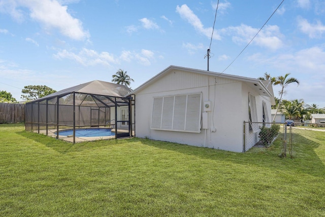 back of house featuring a fenced in pool, glass enclosure, and a lawn