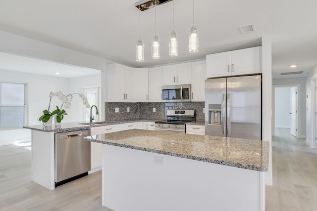 kitchen with sink, white cabinets, hanging light fixtures, a center island, and stainless steel appliances