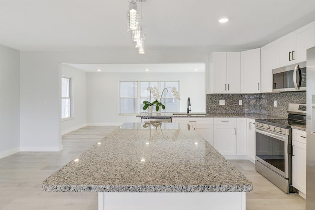 kitchen with sink, decorative light fixtures, a center island, appliances with stainless steel finishes, and white cabinets