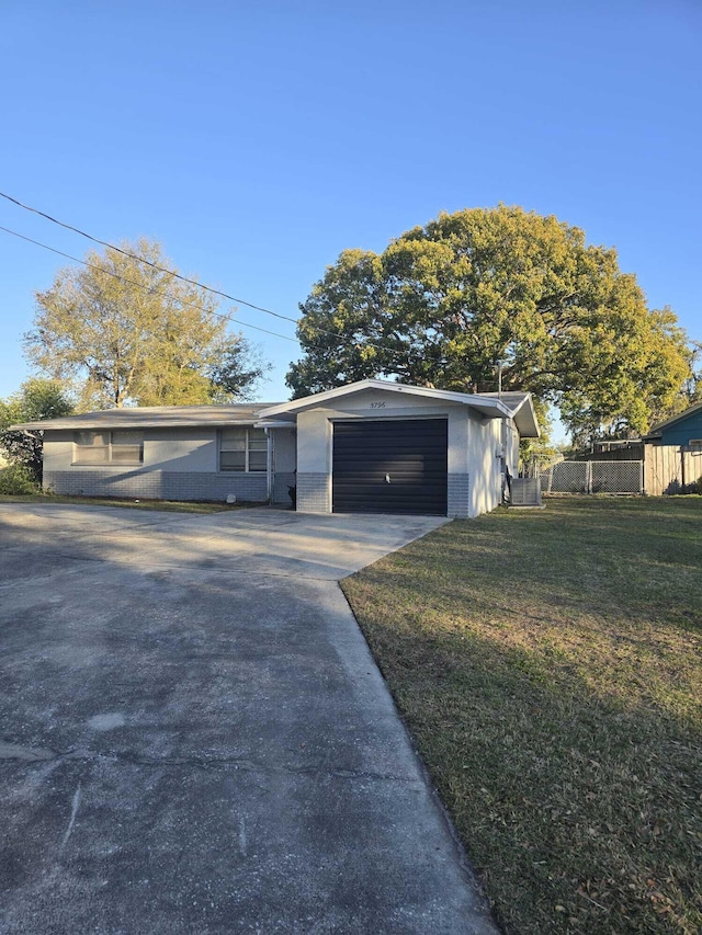 view of front of house featuring a front lawn, fence, concrete driveway, an attached garage, and brick siding