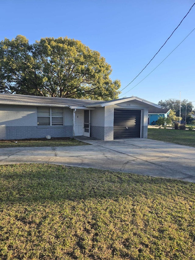 view of front of property featuring a garage, brick siding, concrete driveway, and a front yard