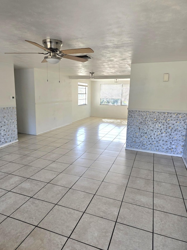 empty room with light tile patterned floors and a ceiling fan