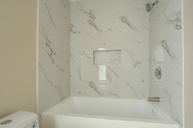 bathroom featuring tiled shower / bath and toilet