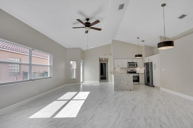 kitchen with appliances with stainless steel finishes, high vaulted ceiling, white cabinets, hanging light fixtures, and ceiling fan