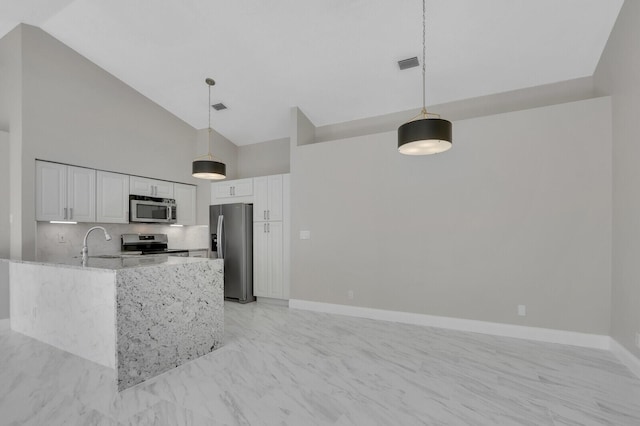 kitchen featuring white cabinetry, light stone counters, hanging light fixtures, appliances with stainless steel finishes, and backsplash