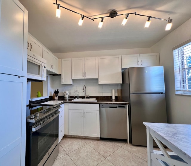 kitchen featuring sink, tasteful backsplash, light tile patterned floors, stainless steel appliances, and white cabinets