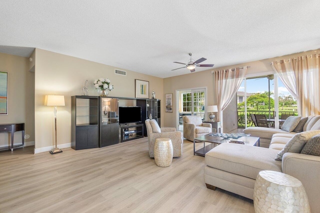 living area with light wood-type flooring, visible vents, a ceiling fan, and a textured ceiling