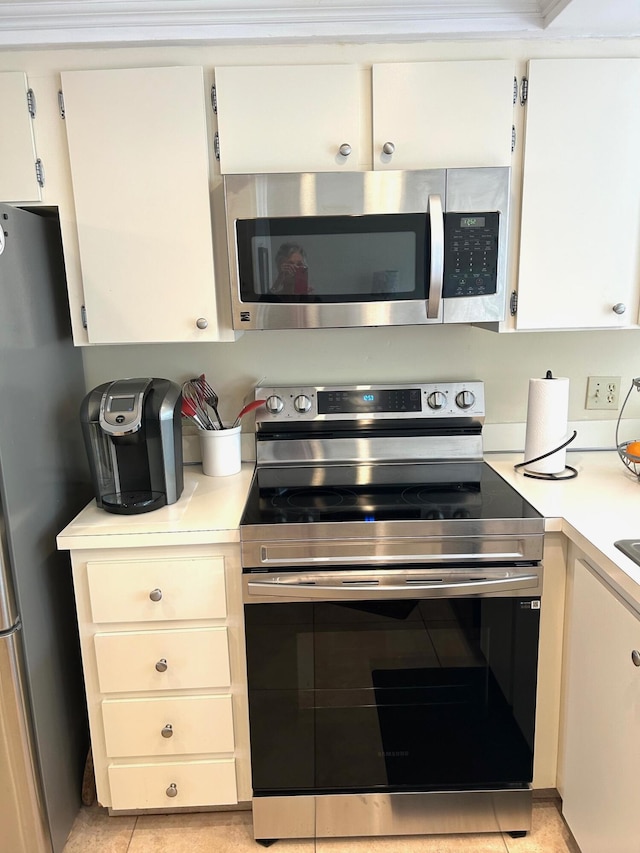 kitchen featuring appliances with stainless steel finishes, light tile patterned floors, light countertops, and white cabinetry