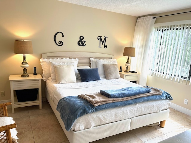 tiled bedroom featuring baseboards and a textured ceiling