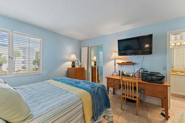 bedroom with light tile patterned floors, a textured ceiling, and connected bathroom