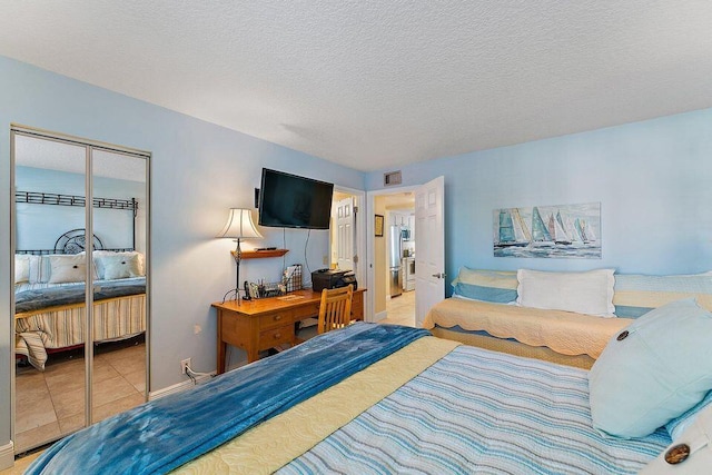 bedroom with light tile patterned floors, a textured ceiling, visible vents, a closet, and freestanding refrigerator