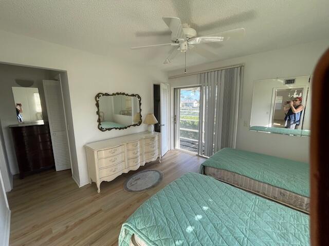 bedroom with hardwood / wood-style flooring, ceiling fan, access to outside, and a textured ceiling