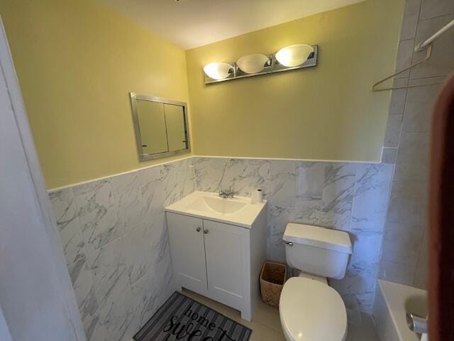 bathroom with vanity, toilet, and tile walls