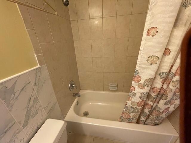 bathroom with tile walls and shower / bath combination with curtain