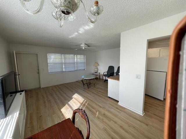 interior space with ceiling fan, a textured ceiling, and light wood-type flooring