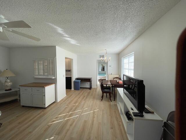 interior space with ceiling fan with notable chandelier, light hardwood / wood-style floors, and a textured ceiling