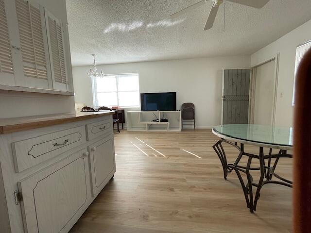 kitchen featuring white cabinets, ceiling fan with notable chandelier, a textured ceiling, and light wood-type flooring