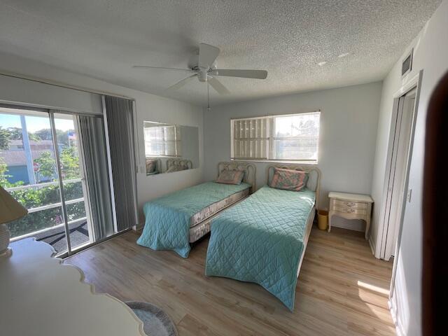 bedroom featuring ceiling fan, access to exterior, a textured ceiling, and light hardwood / wood-style flooring