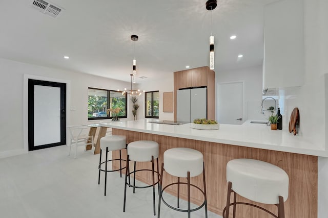 kitchen with sink, hanging light fixtures, kitchen peninsula, and white fridge