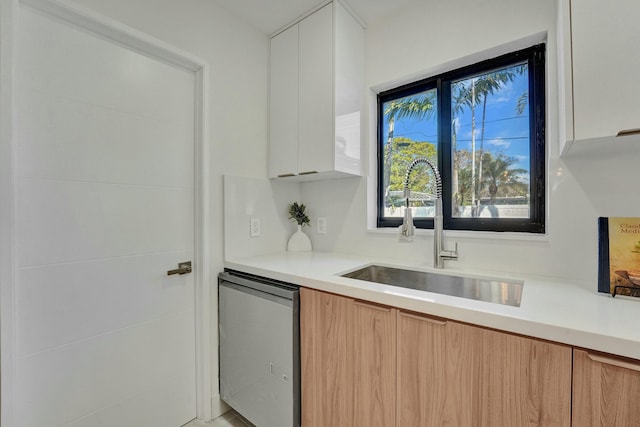 kitchen with white cabinetry, dishwasher, and sink