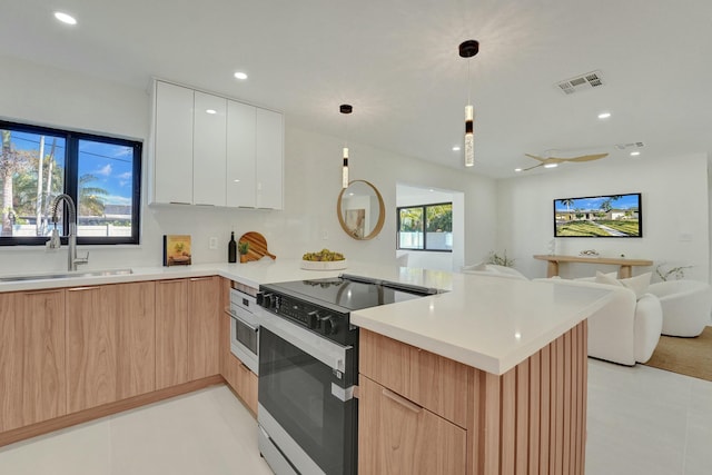 kitchen with pendant lighting, a wealth of natural light, white cabinetry, sink, and electric range