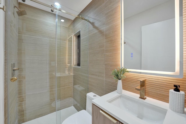 bathroom with vanity, toilet, a shower with door, and tile walls