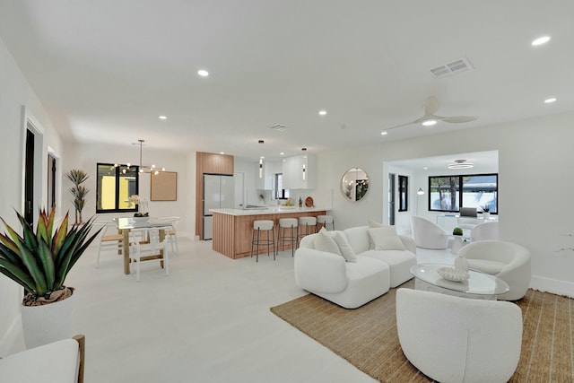 living room with ceiling fan with notable chandelier