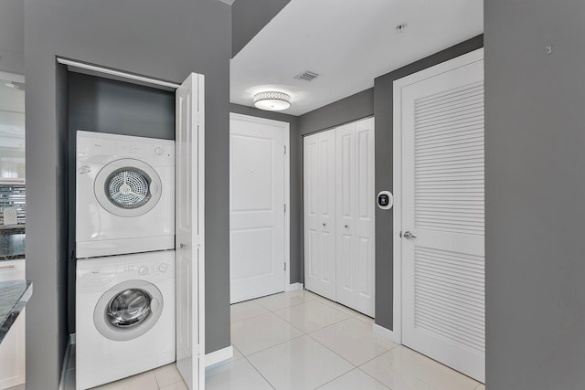 laundry area with stacked washer and dryer, laundry area, light tile patterned flooring, and visible vents