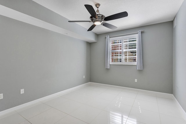 tiled spare room featuring ceiling fan, baseboards, and a textured ceiling