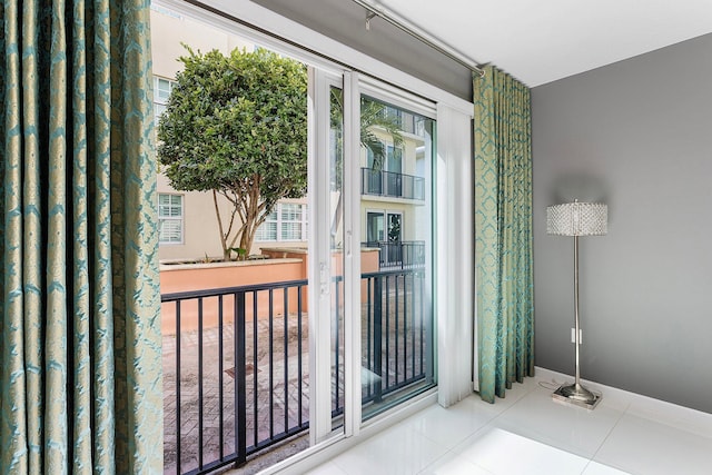 doorway with baseboards and tile patterned floors