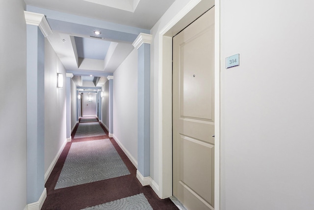 corridor with a tray ceiling and baseboards