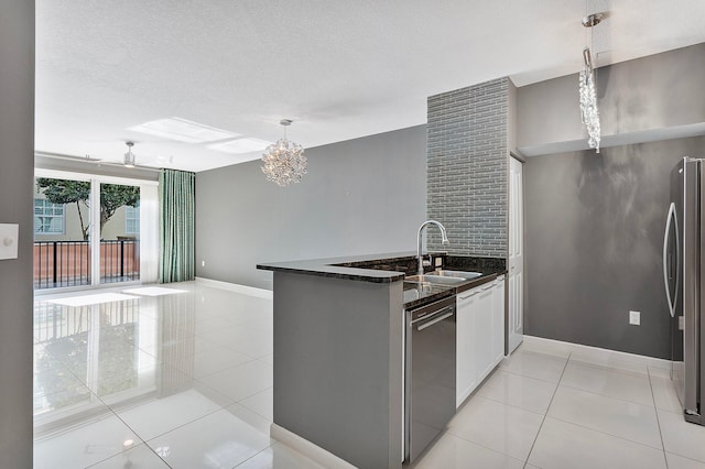 kitchen featuring light tile patterned floors, ceiling fan with notable chandelier, stainless steel appliances, a sink, and pendant lighting