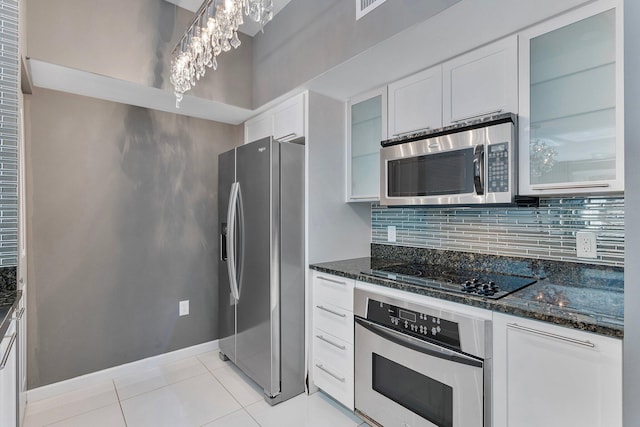 kitchen with light tile patterned floors, white cabinets, appliances with stainless steel finishes, backsplash, and dark stone counters