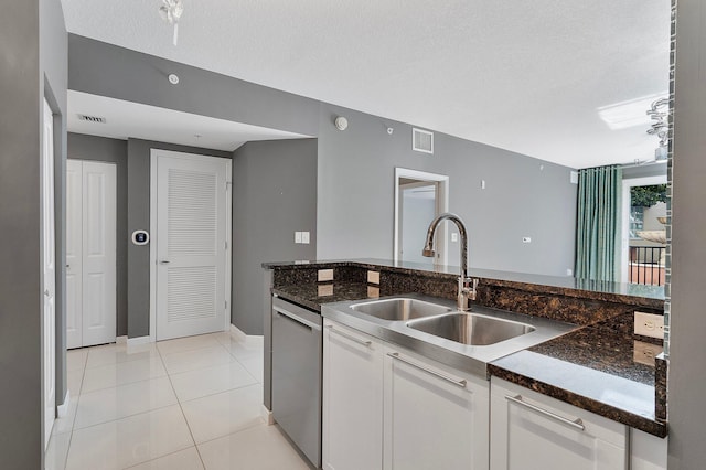 kitchen with visible vents, stainless steel dishwasher, light tile patterned flooring, a sink, and white cabinetry