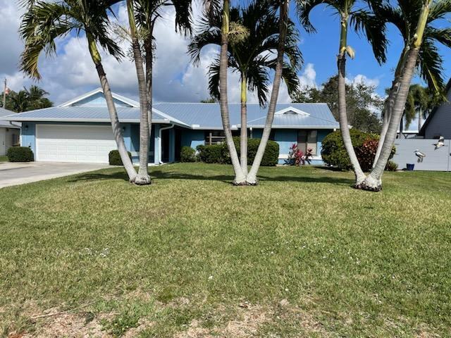 single story home featuring a front lawn, concrete driveway, and an attached garage