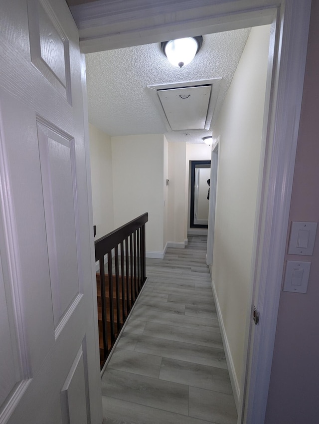 corridor featuring a textured ceiling and light wood-type flooring